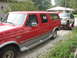 1993 Ford Explorer - A red SUV tows a silver SUV on a trailer down a gravel driveway. The red SUV is a Ford Bronco. The silver SUV is a Ford Explorer.