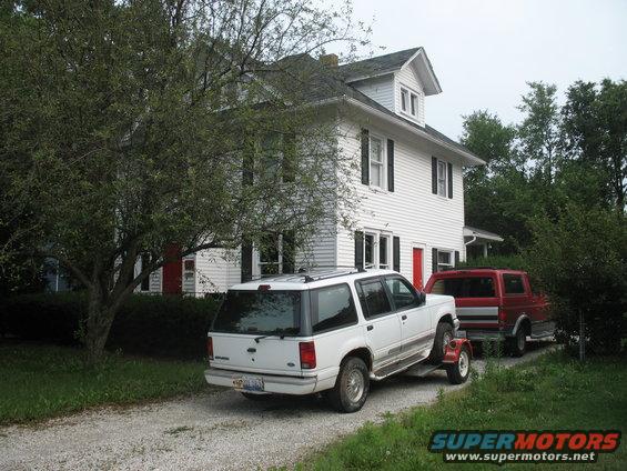 White 1993 Ford Explorer from rear, towing red truck