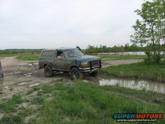 1996 Ford Bronco driving through a muddy trail with a snorkel