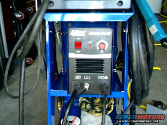 Blue metal frame holding a welding machine with cables attached