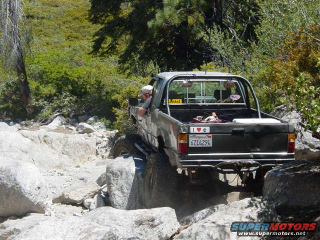 pickup truck driving over rocks on a trail