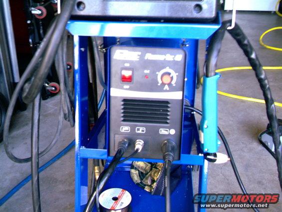 Blue cart holding a welding machine with a red power switch and a dial