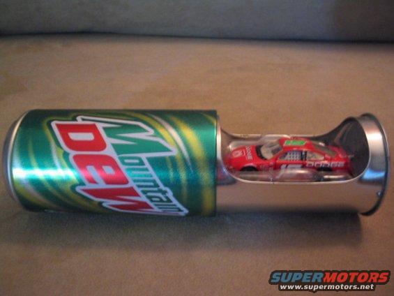 Toy Dodge race car with 'DODGE' text on side, inside a Mountain Dew can