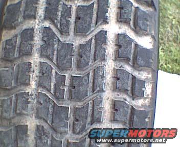 Close-up of a tire tread with Supermotors.net logo