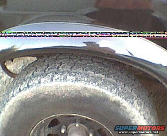 Close-up of a vehicle's tire and fender with chrome trim