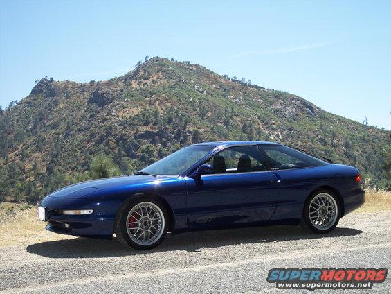 Blue 1995 Ford Probe coupe parked on gravel with a mountain in the background