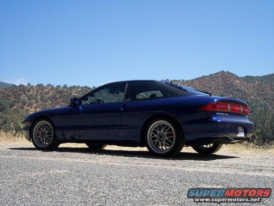 Blue 1995 Ford Probe parked on a gravel road with hills in the background