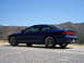 1995 Ford Probe - A blue 1995 Ford Probe is parked on a gravel surface with a hilly landscape under a clear blue sky.
