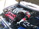 1995 Ford Probe - The engine bay of a blue 1995 Ford Probe is shown, a V6 engine with red valve covers and a silver intake manifold.