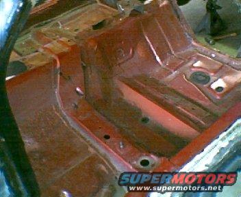 Interior floor pan of a car undergoing restoration. Red primer visible