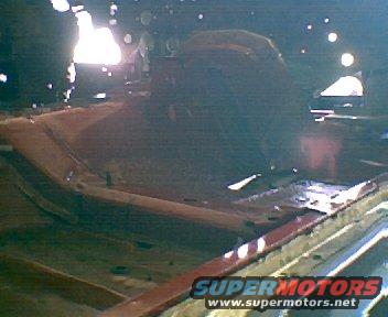 Vehicle interior under construction, showing rusted floor pans and exposed metal