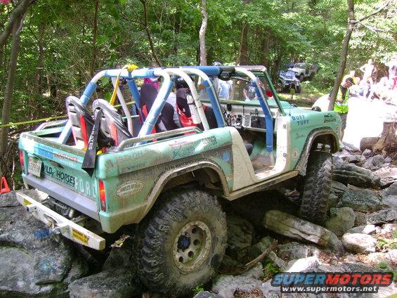 Mint green off-road vehicle with roll cage navigating a rocky trail. Another vehicle is visible further back on the trail