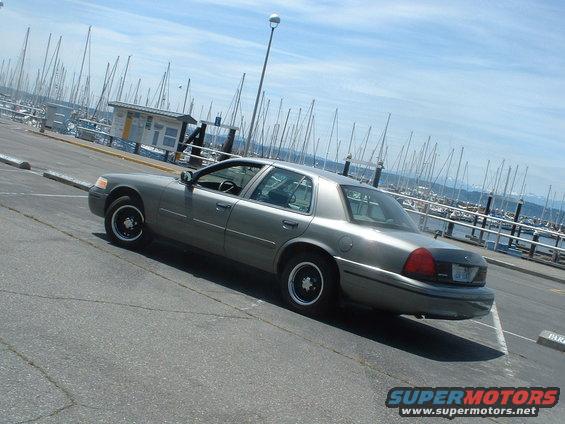 Gray 2000 Ford Crown Victoria parked near a marina with sailboats in the background