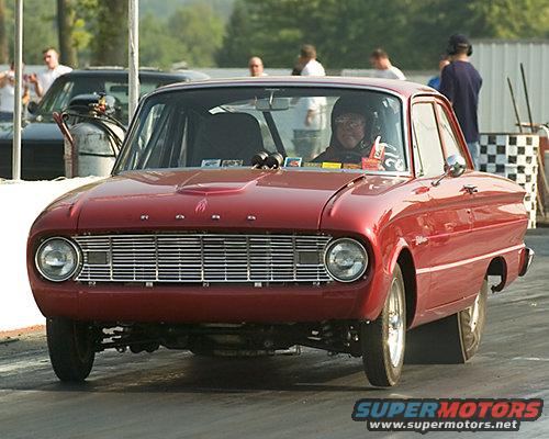 1960 Ford Falcon drag car with racing slicks and a roll cage, driver wearing helmet