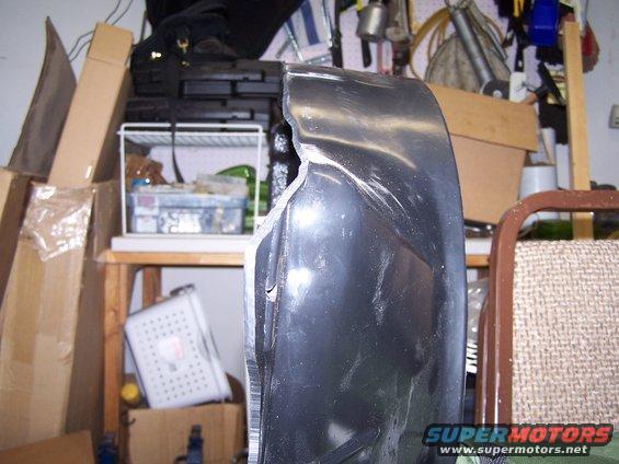 Damaged black fender in a cluttered garage