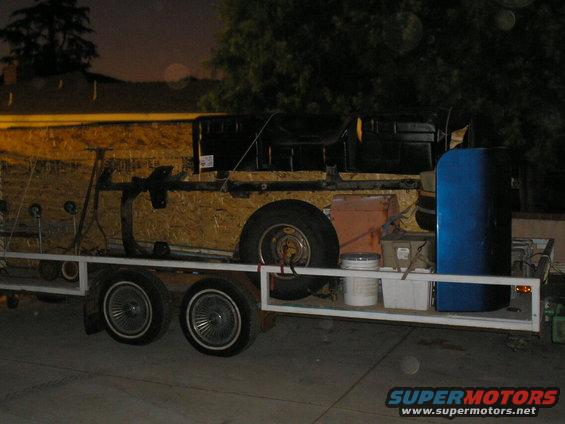 Trailer loaded with wood, metal frame, blue barrel, and buckets
