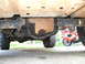 1994 Ford Bronco - The underside of a vehicle is shown, with a motorcycle partially visible in the background.