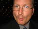 1988 Ford Bronco - A man in a suit and glasses puckers his lips for a photo in front of a dark, dotted background.
