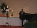 1988 Ford Bronco - A man speaks at a grand piano, with a candelabra and guests visible in the background.