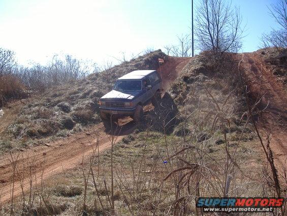 Dark SUV driving down a dirt hill, front grille visible