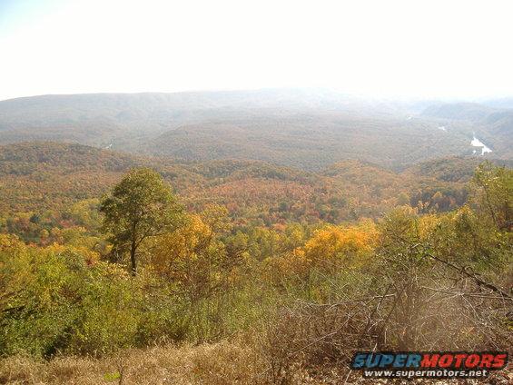 Hazy mountain landscape with trees in autumn colors and a distant river