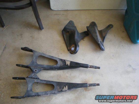 Pair of front suspension control arms with "W" emblems and two mounting brackets