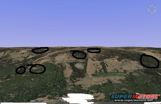 Overhead view of a hilly landscape with black circles marking areas of interest