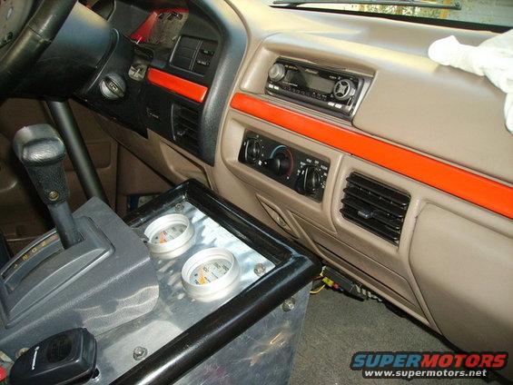 Interior view of a truck's dashboard with aftermarket gauges and orange trim