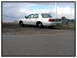 1998 Ford Crown Victoria - A silver 1998 Ford Crown Victoria sedan is parked on a dirt lot with a cloudy sky overhead.