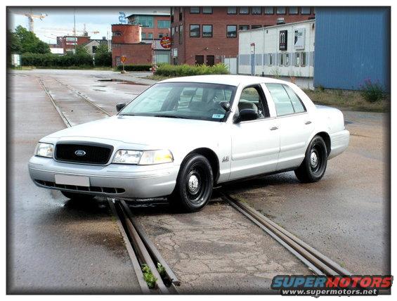 White sedan with black wheels on train tracks, front 3/4 view