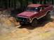1979 Ford Bronco - This red Ford Bronco is navigating a sandy, off-road trail with trees in the background.