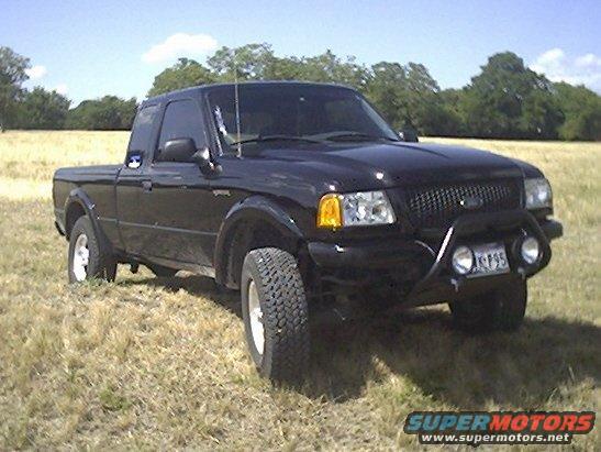 Black 2002 Ford Ranger pickup truck with aftermarket bull bar and fog lights, parked in a grassy field