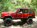 1996 Jeep Cherokee - A red 1996 Jeep Cherokee navigates a challenging rocky trail with a driver behind the wheel.