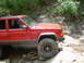 1996 Jeep Cherokee - A red 1996 Jeep Cherokee is shown off-roading on a rocky trail.