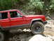 1996 Jeep Cherokee - A red 1996 Jeep Cherokee navigates a challenging rocky path, demonstrating its off-road capabilities.