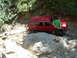 1996 Jeep Cherokee - A red Jeep Cherokee navigates a difficult off-road path, getting stuck between large rocks and mud.