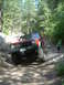 1996 Jeep Cherokee - 1996 Jeep Cherokee navigating a challenging off-road trail with large rocks and trees.
