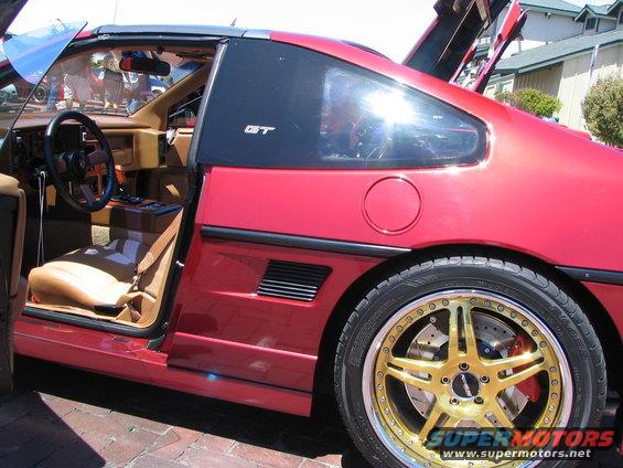 red Pontiac Fiero GT with doors and engine cover open, tan interior, gold rims