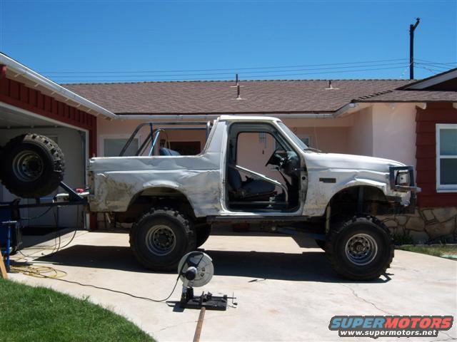 White SUV with rollcage, spare tire on rear, side view