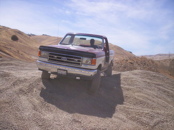1987 Ford F-150 pickup truck with two-tone paint, parked on a gravel hill