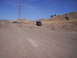 1989 Ford Bronco - A maroon Ford Bronco is parked on a dirt road, with rolling hills and a large power line tower under a clear blue sky.