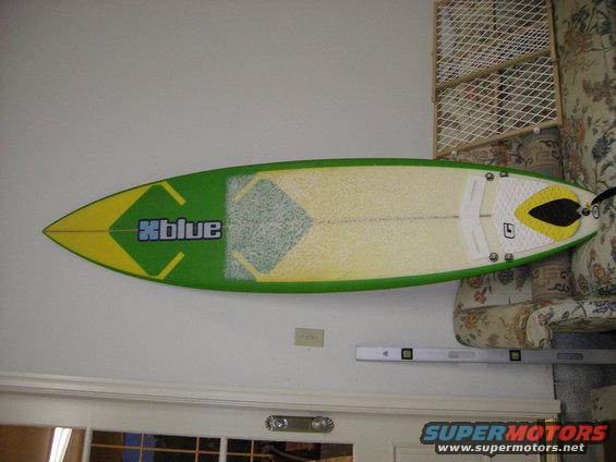 Green and yellow surfboard with 'Xblue' logo mounted on a wall