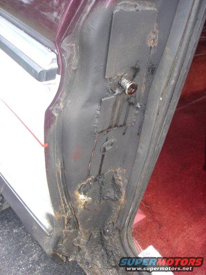 rusted out door jamb area of a vehicle, showing significant corrosion and damage