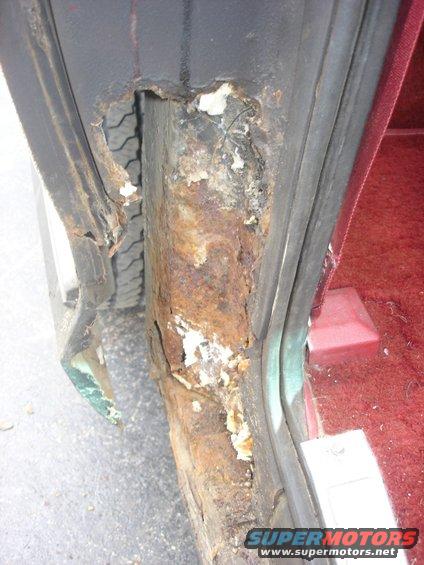 Heavily rusted door jamb with visible tire tread behind it