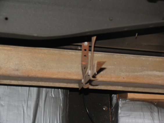 Close-up of a rusty metal running board mounting bracket attached to a vehicle frame