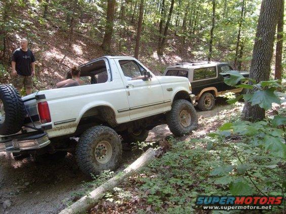 White 1992 Ford Bronco driving off-road, spare tire mounted on rear