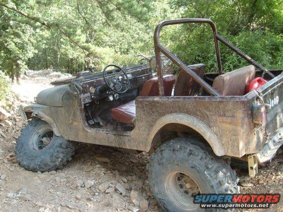 Jeep CJ-7 with roll cage and large tires on a rocky trail. Red gas can in the back