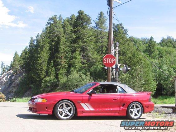 Red convertible Mustang side view with a grey top