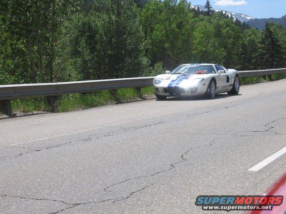 White 2005 Ford GT with blue stripes on a highway, front quarter view