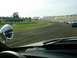 1993 Ford Mustang - A view from the driver's seat of a race track with multiple cars on the course and empty grandstands.